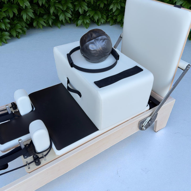 Close up of Carriage for Milaron Maple Studio Reformer with jumpboard attached and additional accessories sitting on top of carriage