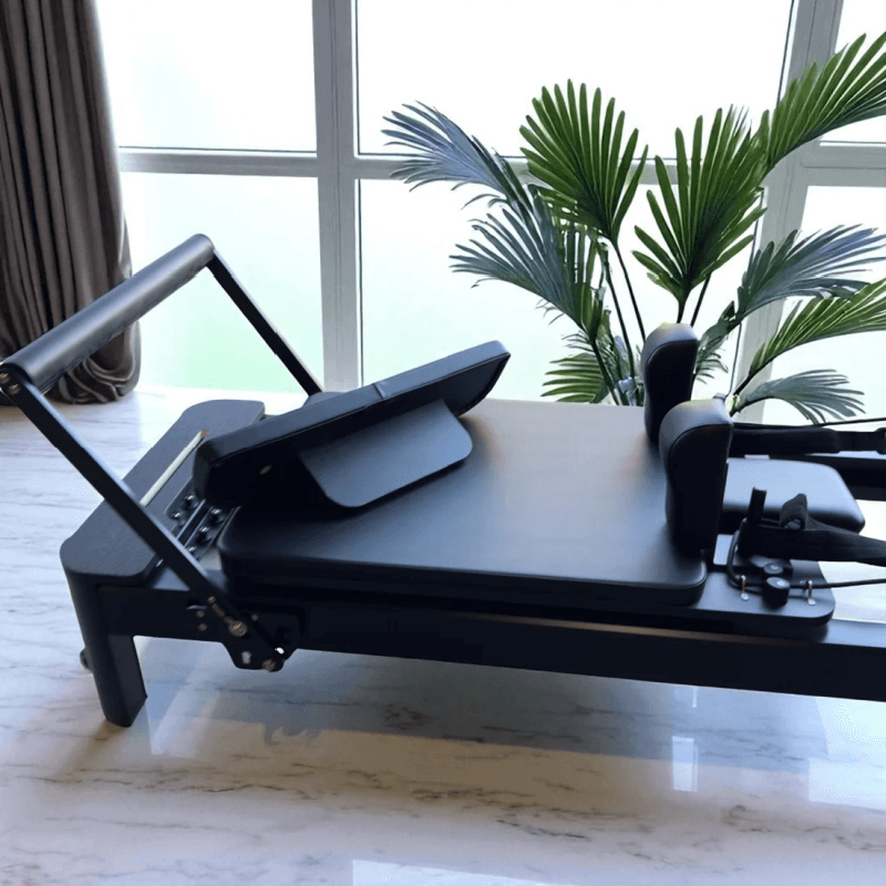 Side view close up of pilates reforem with black carriage with footboard on carriage