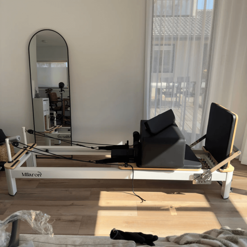 Full side view of Milaron Pearl Reformer at home with sitting board resting on carriage and jumpboard attached