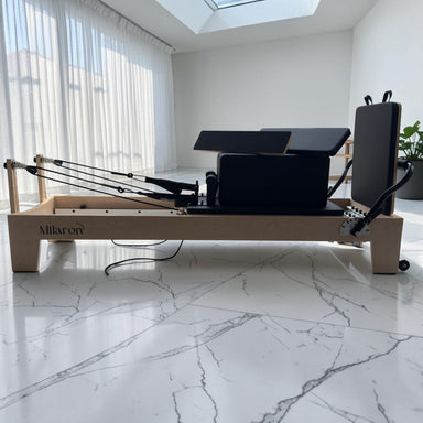 Side profile of the Milaron Maple Studio V3 reformer showing the full carriage and spring platform