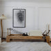 Wooden pilates reformer with beige upholstery in a room with a lamp and wall art