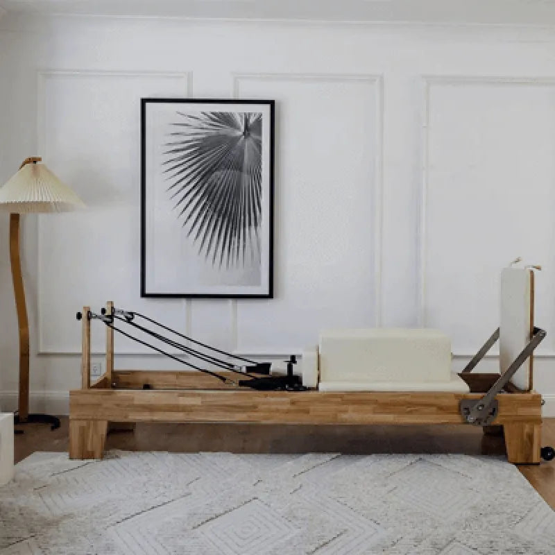 Wooden pilates reformer with beige upholstery in a room with a lamp and wall art