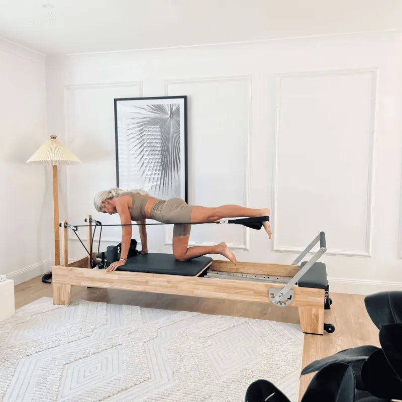 Woman on wooden pilates reformer machine doing leg exercises
