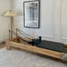 Wooden pilates reformer bed with black upholstery in home living room setting