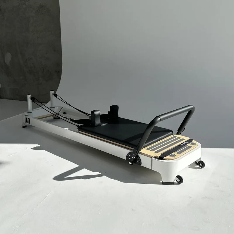 Core Collab Queen 2.0 Pilates reformer machine with white frame and black carriage on a light gray photo shoot background