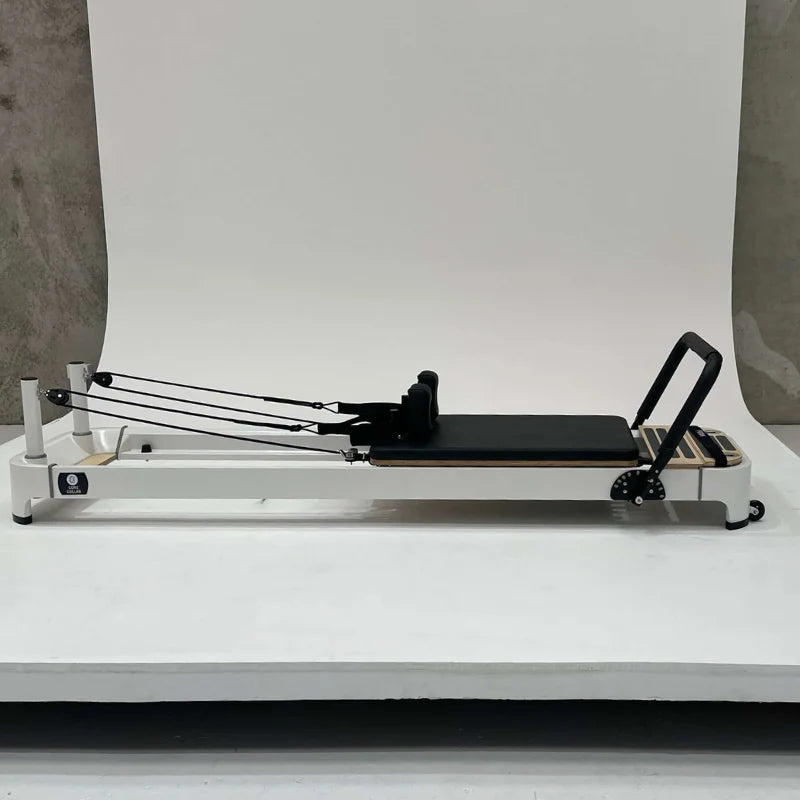 Core Collab Queen 2.0 Pilates reformer machine with white frame and black carriage direct side profile on a light gray photo shoot background