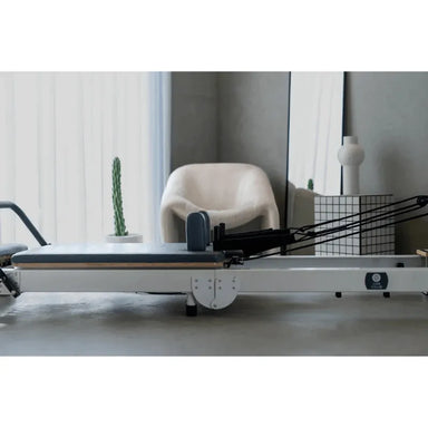 Full Side View Queen Foldable Reformer with white frame and grey upholstery in open position in home studio setting showing full carriage and frame