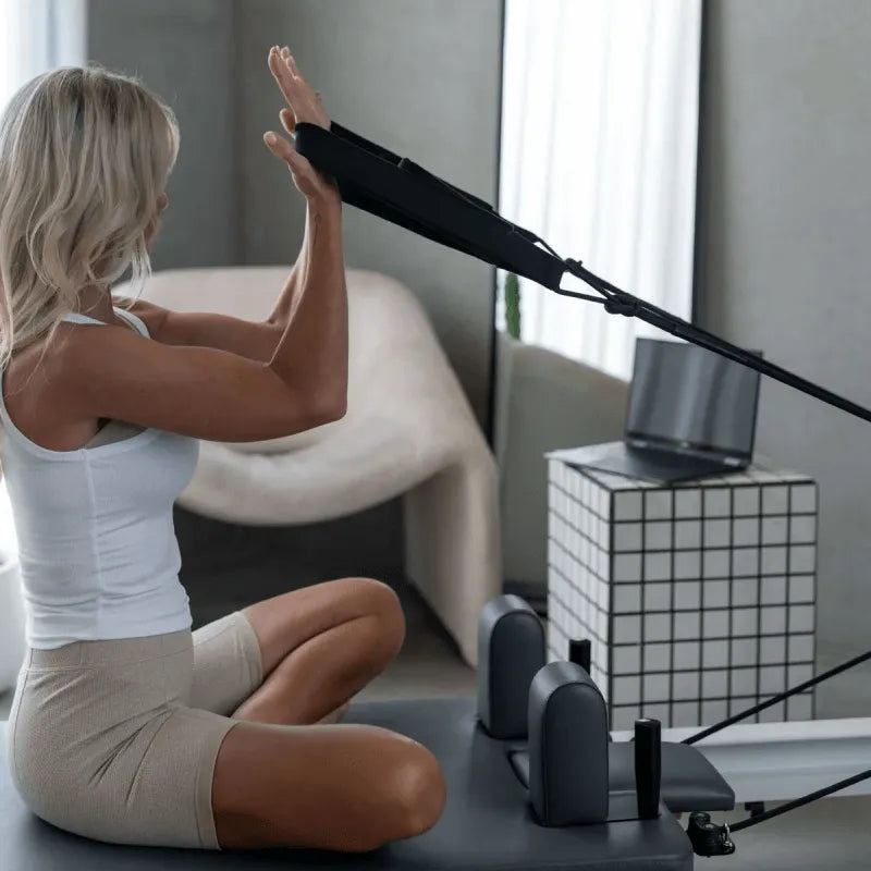 Woman using a Pilates reformer machine in a home setting.