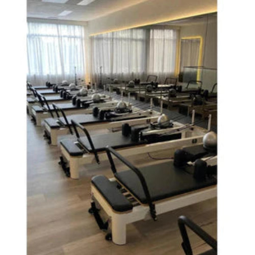 Line up of multiple Core Collab Queen Studio reformers set up in pilates studio