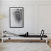 In situ image of Core Collab Reformer machine in living room with rug and painting
