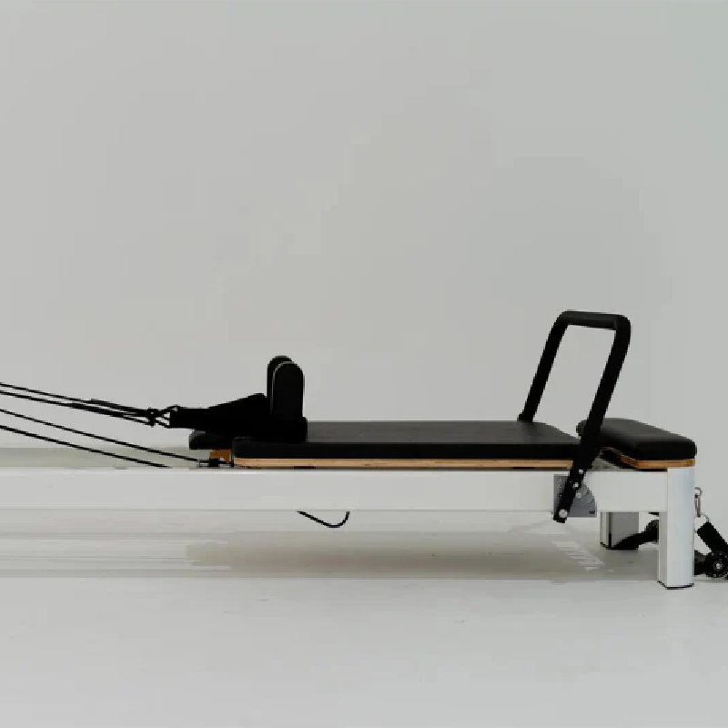 Close up of Carriage area of pilates reformer with white frame and black upholstery on white background