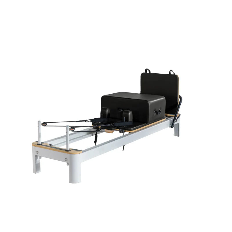 Flatlay image of Core Collab Queen Studio in black on white showing full view of reformer at front side angle with accessories attached