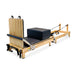 Full Angle Side View of the Impact Fitness Foldable Pilates reformer with black carriage and oak frame showing back view of jumpboard