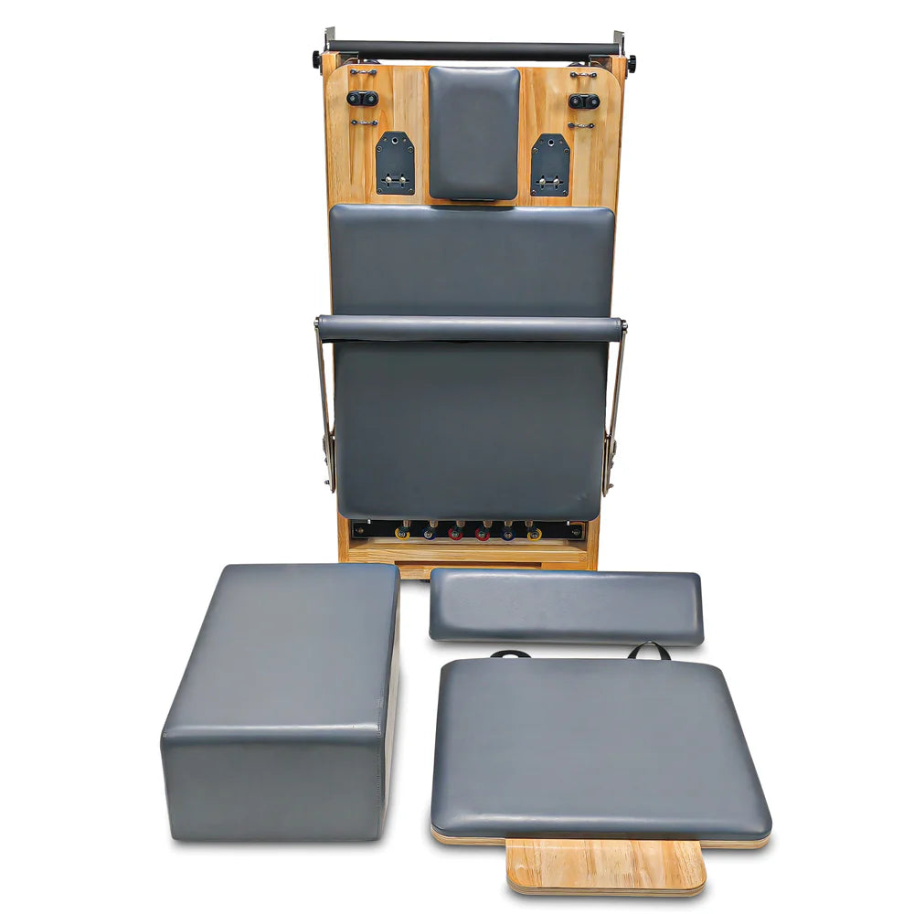 Folded upright front view of Impact Fitness foldable reformer in Dark Grey with sitting box, foot pad and jumpboard