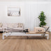 White Aluminium Contour Pro Pilates reformer machine in a living room setting with a couch and plant.