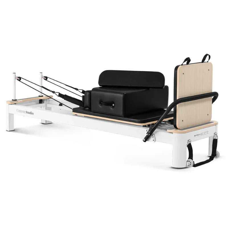 White pilates reformer with black leather on white background with sitting box and jumpboard attached