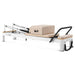 Side view of pilates reformer on white background with sitting box and footbar up