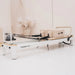 Side view of white pilates reformer with beige leather in a minimal studio