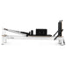 Direct side view of whie pilates reformer with black leather on white background