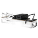 Side view pilates reformer with white frame and black upholstery with footbar up
