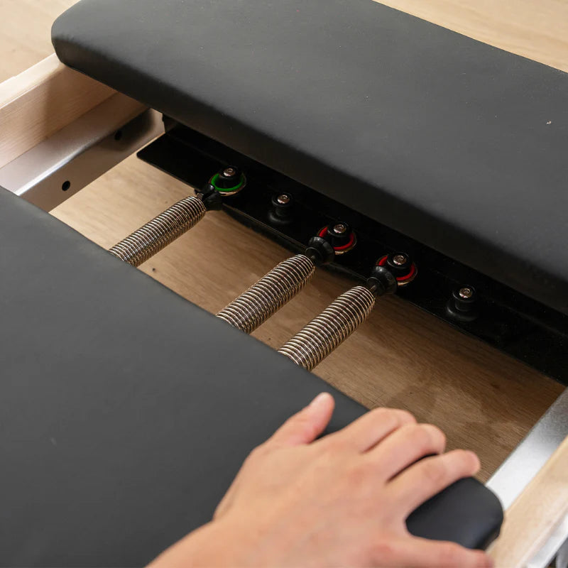 Close-up of a person's hand movig carriage of black reformer bed.