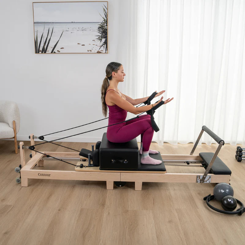 Woman exercising on a Lifespan Fitness Wooden reformer machine in a home setting
