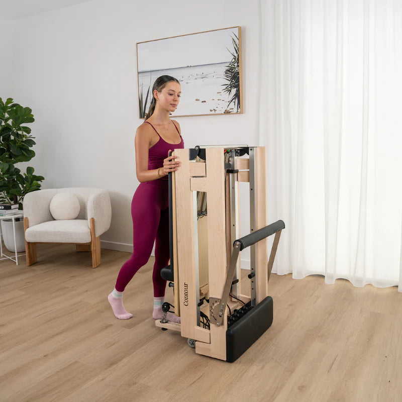 Woman Folding Lifespan Fitness Wooden Contour Reformer in Home Living Space
