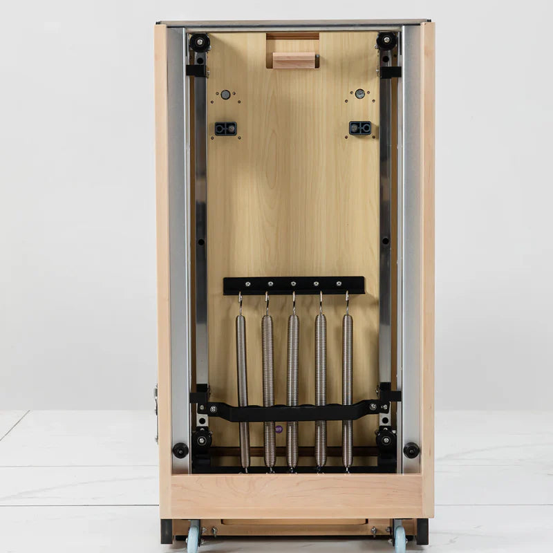 Folded Wooden Pilates Reformer showing underneath view of springs and machine on white background