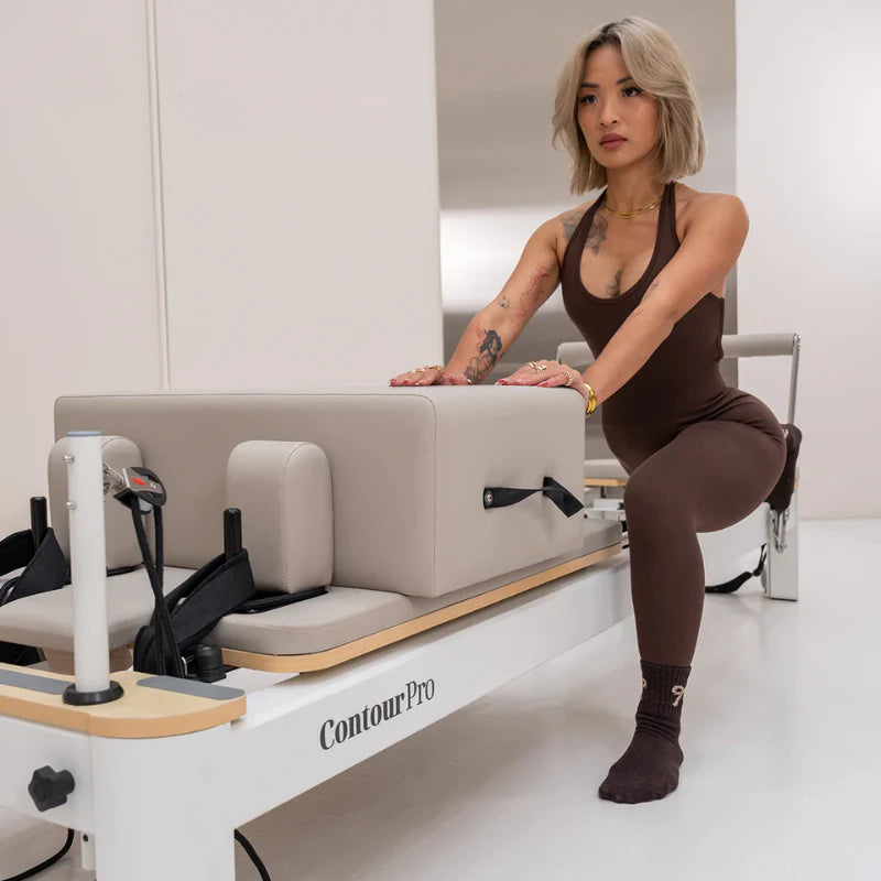 Woman doing lunges on beige and white aluminium reformer