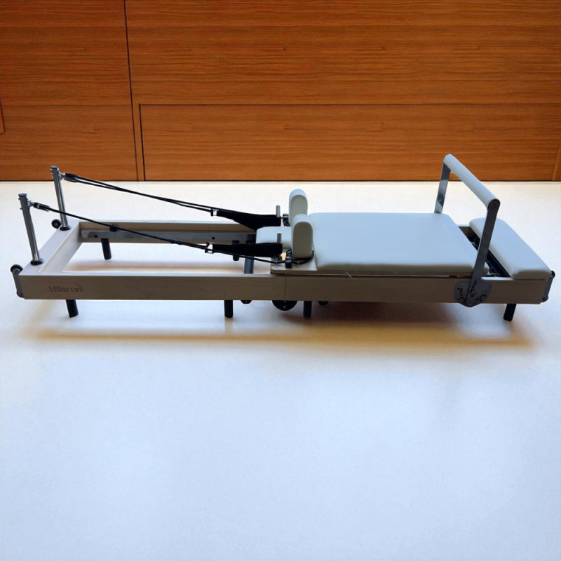 Full side view of Milaron Maple Foldable reformer in studio setting with straps hooked on to hooks near headrest