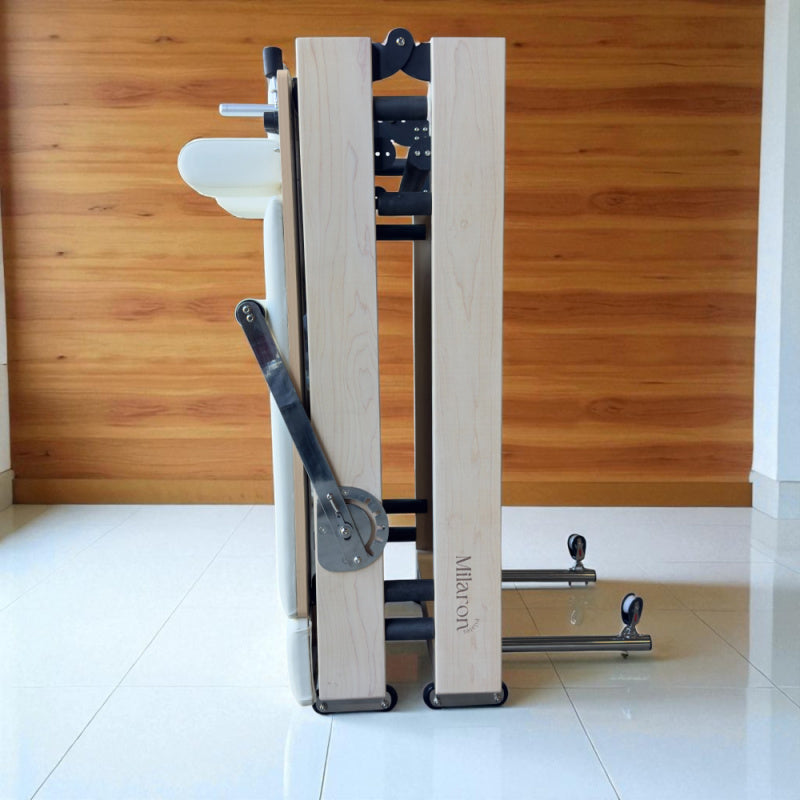 Side profile view of creme Milaron Maple Foldable reformer in folded position standing upright.