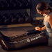 Woman using Black Therabody RecoveryAir Jetboots PRIME product in a gym setting