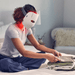 Lady on bed folding washing wearing Theraace Mask with red LED light