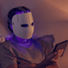 Male sitting in bed reading kindle with white Theraface Mask on with blue LED lights