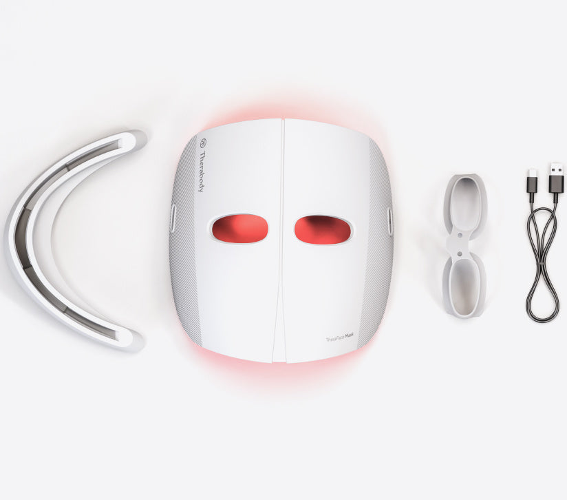 Flatlay of the Theraface LED Mask with goggles and cord and base attachments